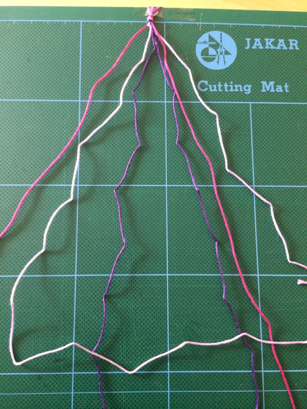 Then feed the end of the lilac thread over and under the purple thread to make a loop and pull to the top to create a knot. Repeat it again to create a double knot on the same thread.
