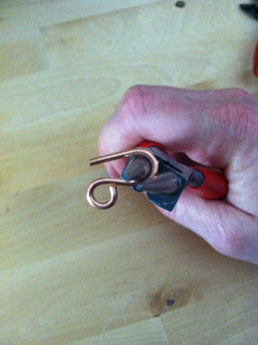 Then grasp the wire with the round nose pliers about 1/4" above the loop and use your fingers to bend the remaining wire around the head of the tool to form a hook.