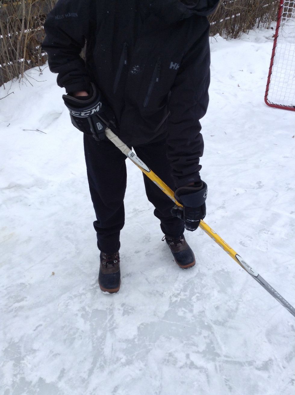 Then, hold your hockey stick with one hand slightly higher than half way down and the other hand at the top of the stick.