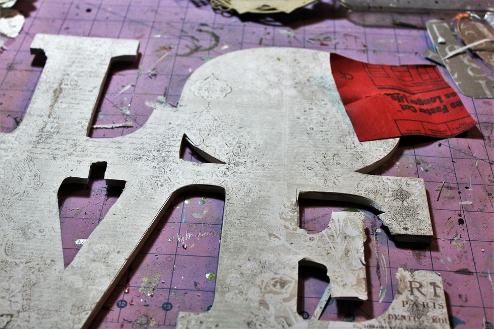 Then, I used spray adhesive to adhere a 12 x 12 sheet of patterned paper from the main kit to the front of the LOVE. I sanded the edges.