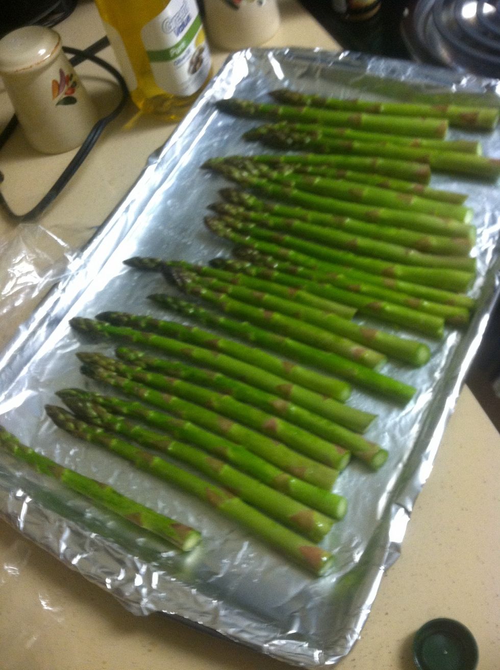 Then lay out the asparagus and roll them in the olive oil, then sprinkle salt and pepper.