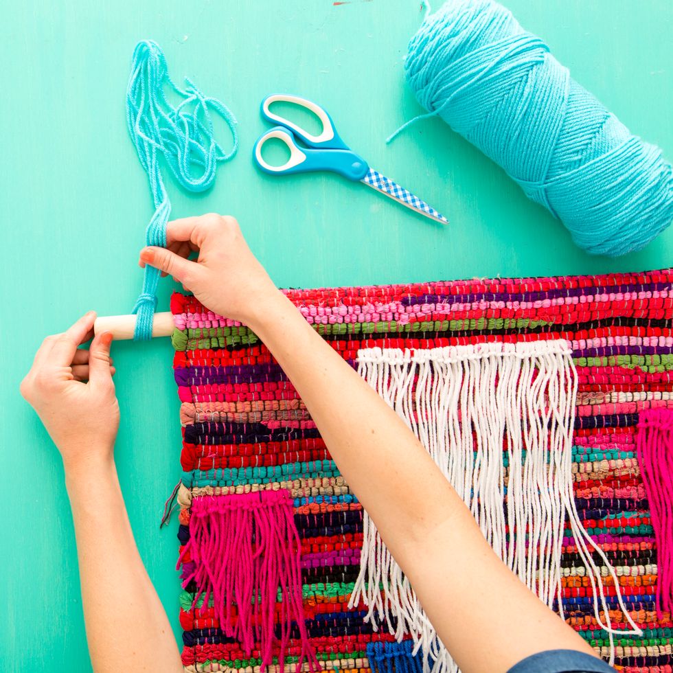Then, loop more yarn around the two edges of the dowel, then tie these pieces together in a firm knot. Hook this knot on the wall, then call it a day!