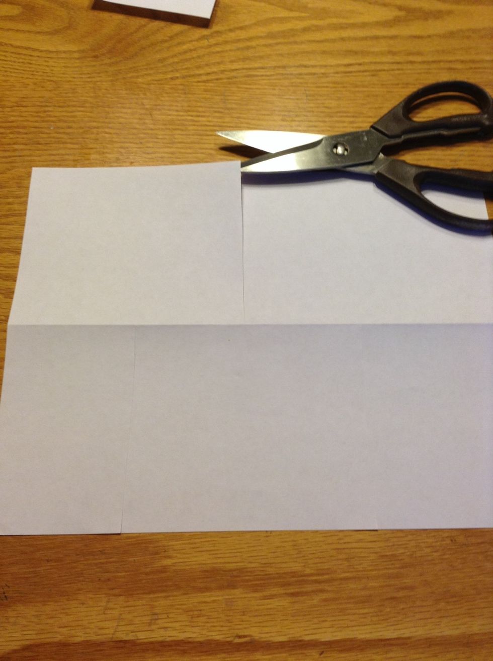 Then make a cut on the top half of the paper that goes down directly in the center of the two bottom cuts. Make sure that the cut goes all the way down to the crease.