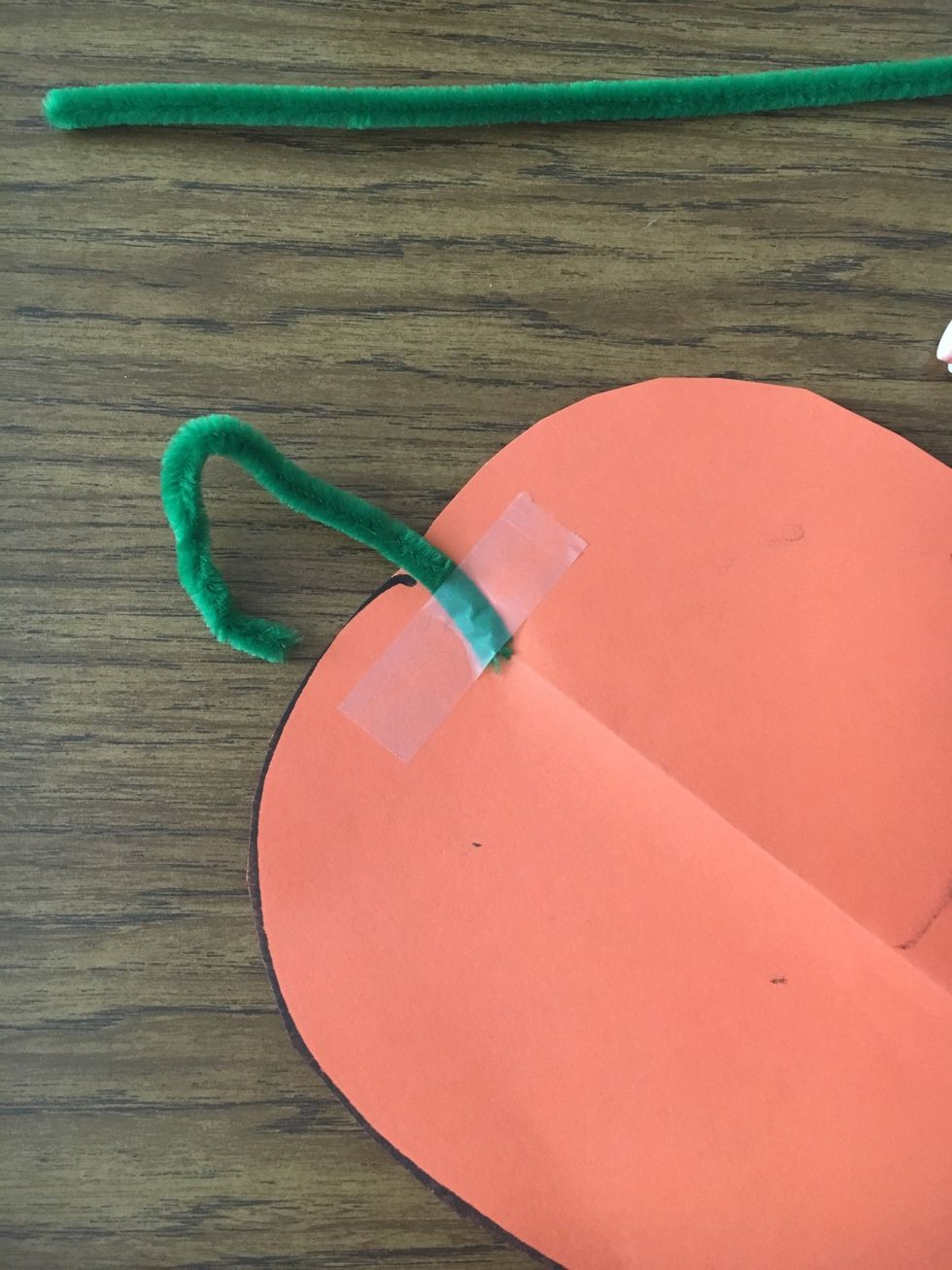 Then, on one side of the circle, tape the candy cane pipe cleaner at the top. The candy cane part should be seen (rounded part).