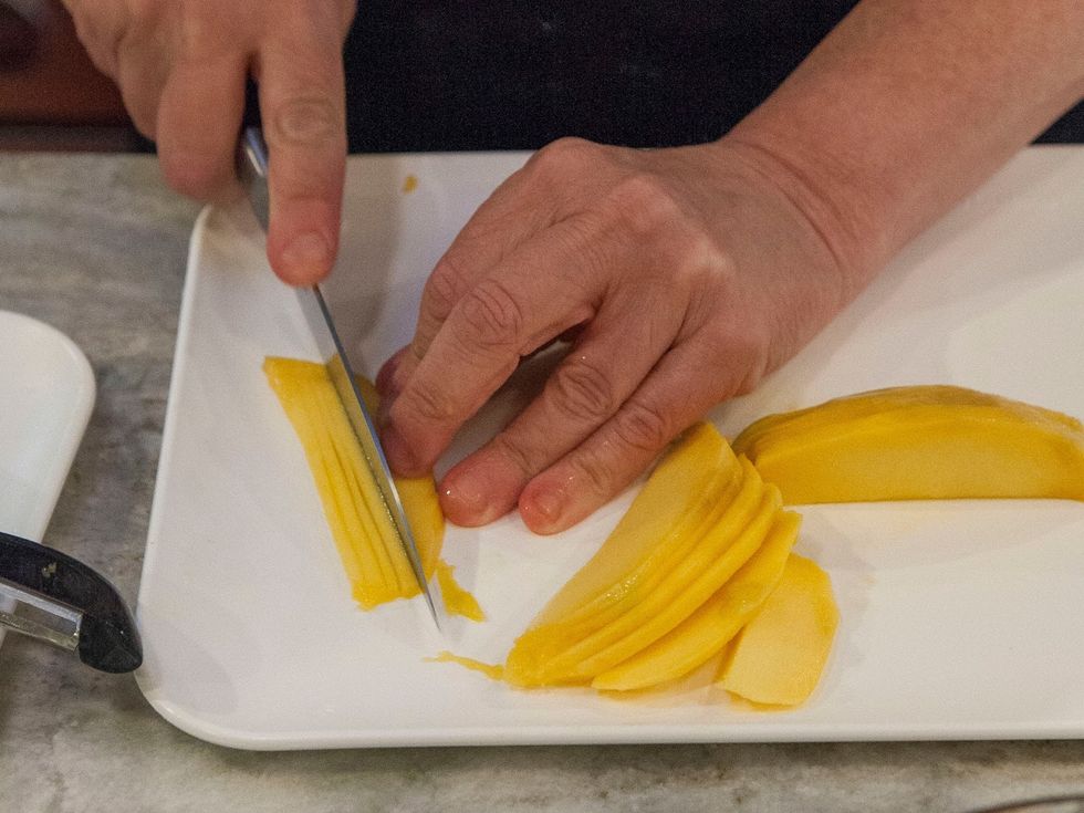 Then peel and thinly slice your mango. Arrange the peeled slices fan like on a plate. Add the chickpea coconut salad mixture to the top of that.