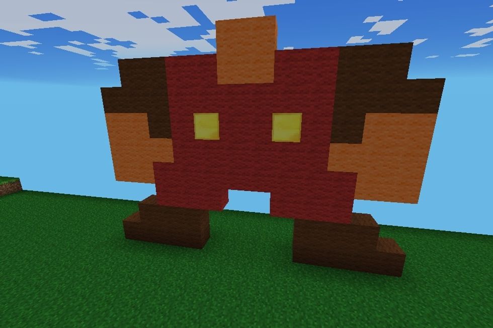 Then place the rest of the red wool for the dungarees and put two gold blocks in the middle for buttons. Start the neck out of orange wool