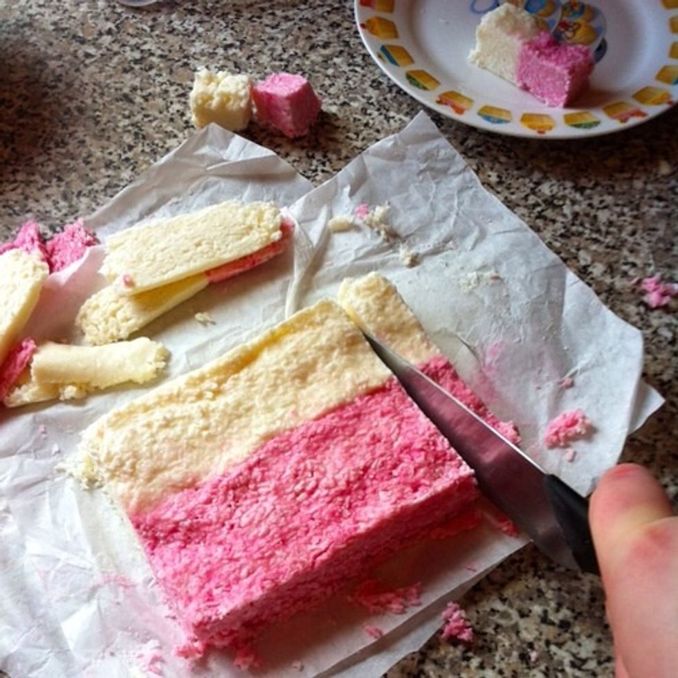 Then pop this in the fridge and leave to set for 2-3 hours. For best results, leave overnight. Cut the edges off (and eat them.) And then cut your coconut ice into lovely little slices!