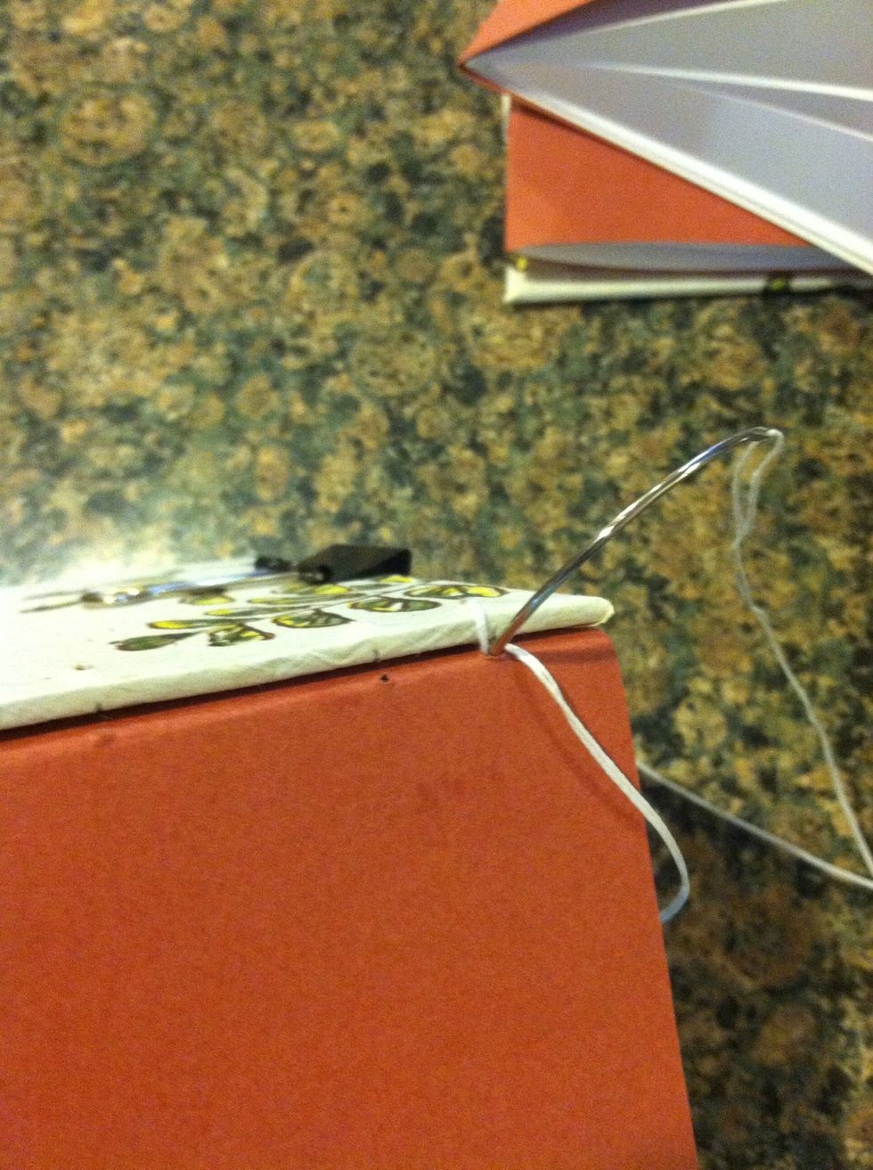 Then push needle through the same hole in the paper