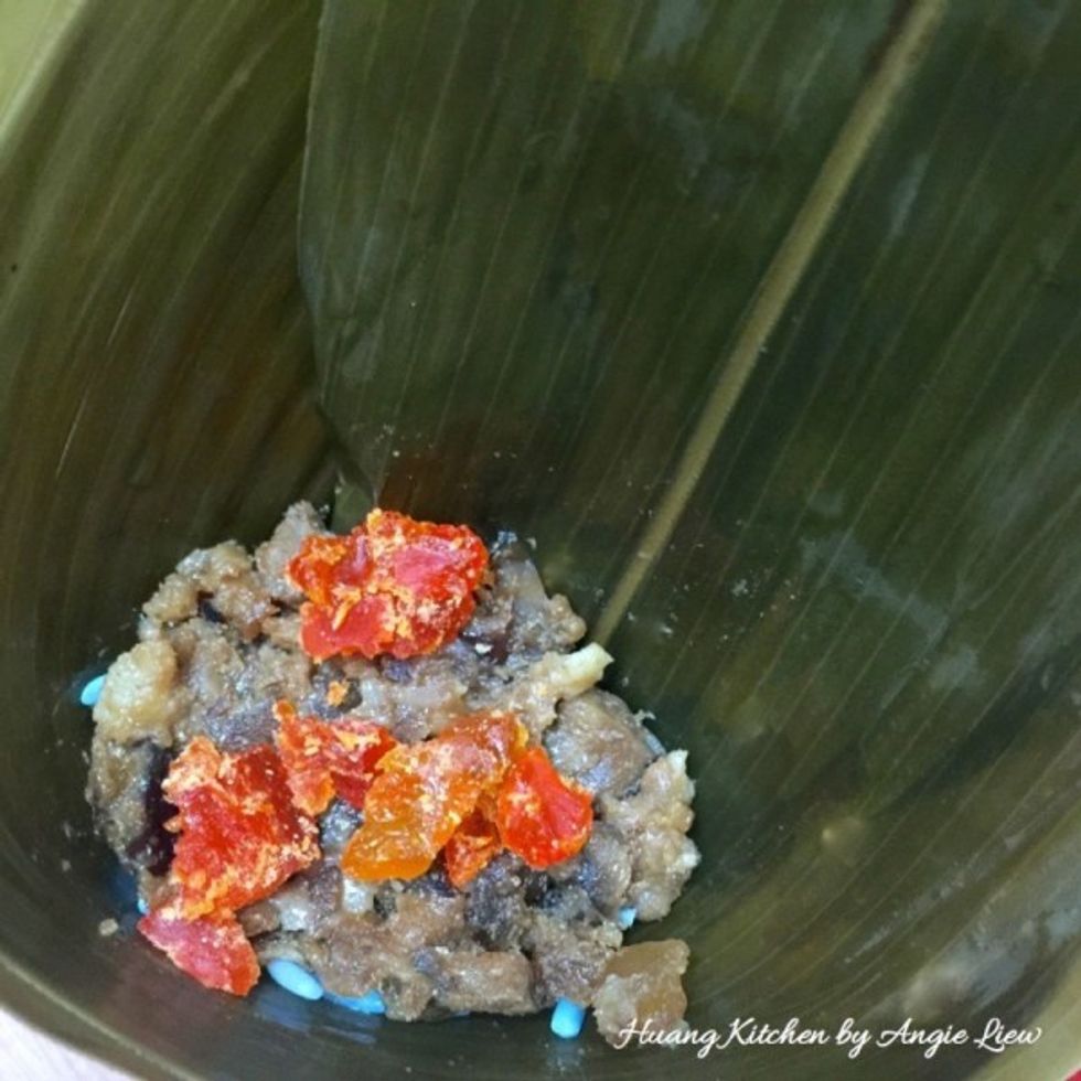 Then put 1 tbsp of pork filling and 1 tsp of chopped salted egg yolk to form a layer of filling.