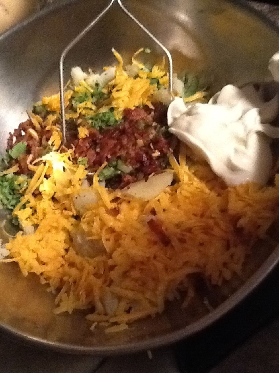 Then put the bacon,broccoli,your 1/2 cup shredded cheese,and sour cream,with your mashed potato inside then,stir together.and a little salt and pepper to taste.