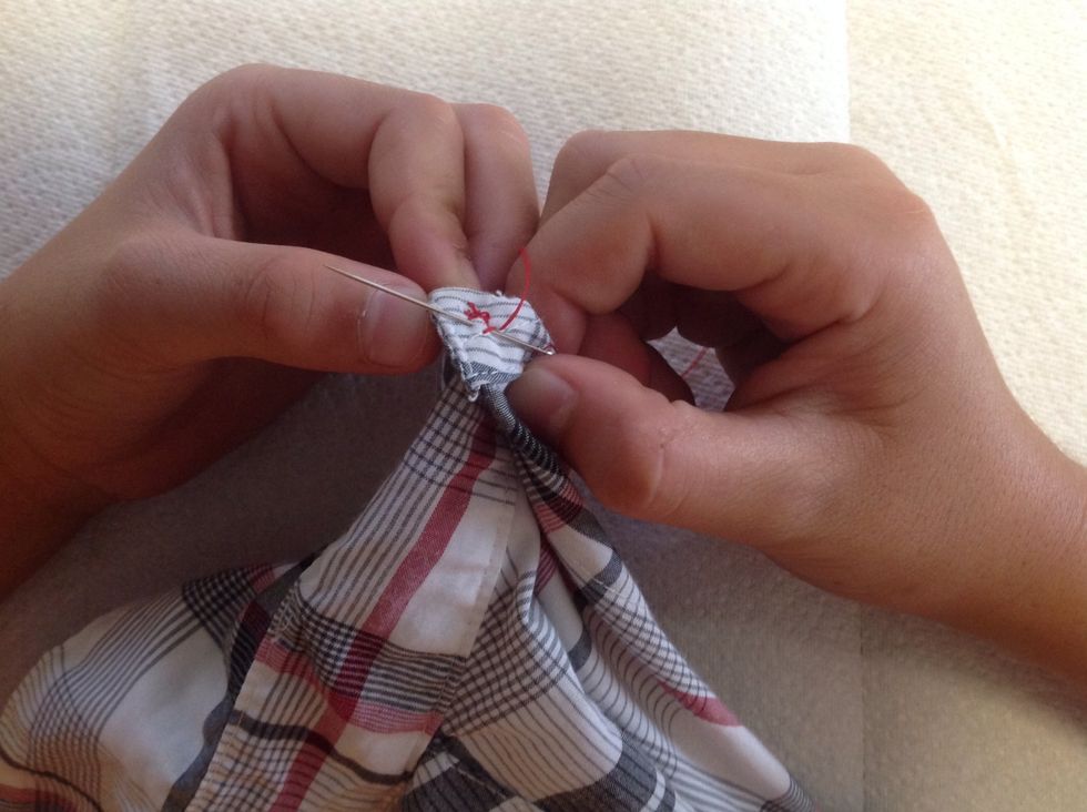 Then put the needle through a little of the stitching and through the material.