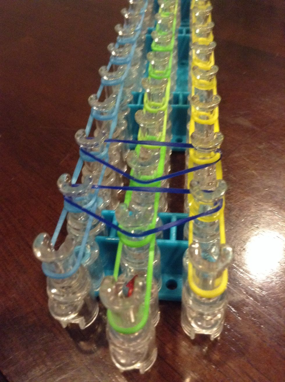 Then, put upside down rubber band triangles on the loom. Skip the first 3 in the front