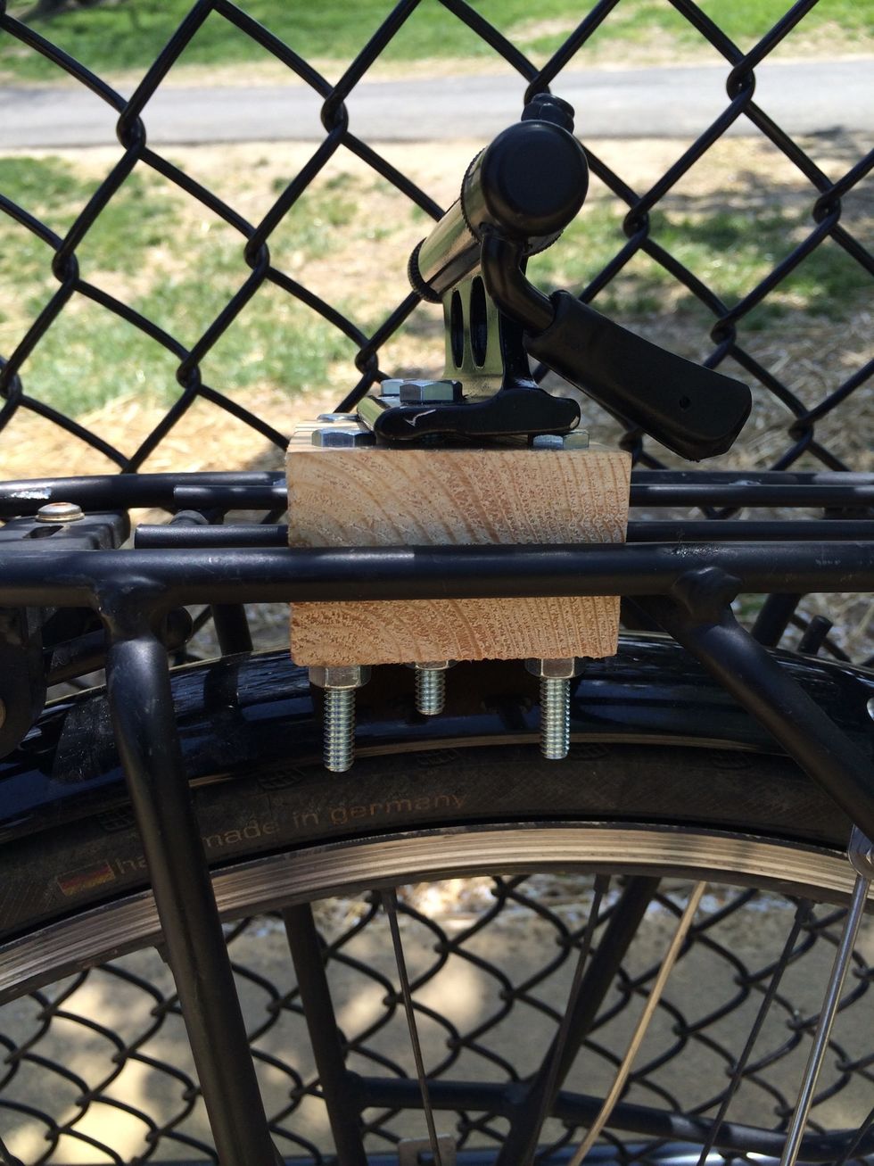Then, sandwich the cross bars of your bicycle rack with two 4.5 inch 1x3 pieces of plywood. You'll drill a 1/4 inch size hole in all four corners, run your bolts through them, and screw on your nuts.