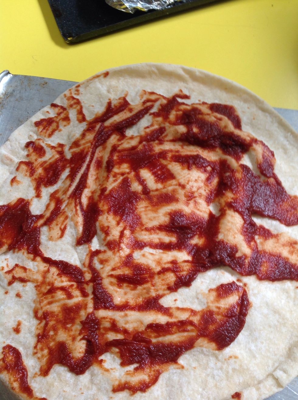 Then spread the tomato paste on the pizza with a spoon or a knife.