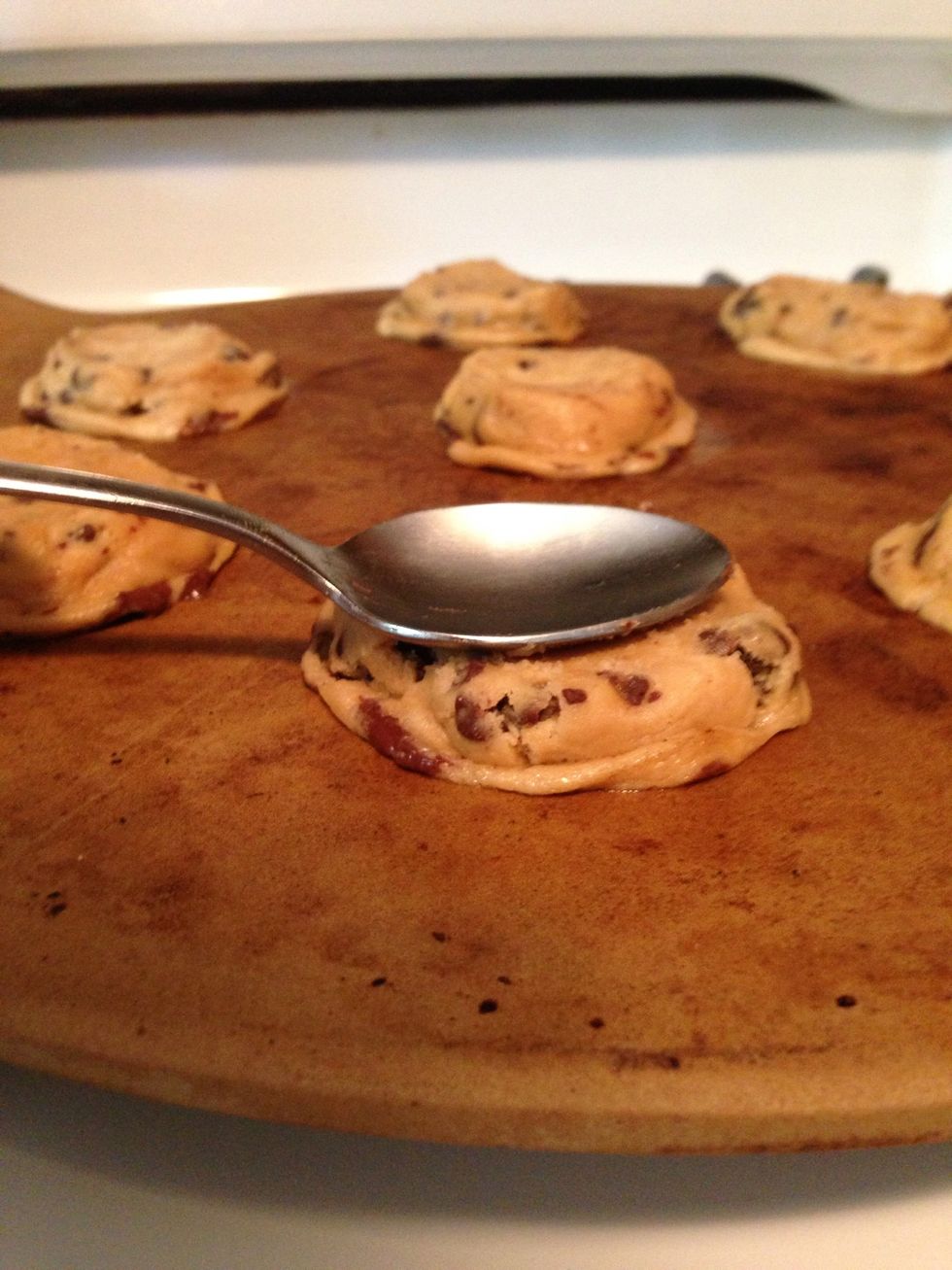Then take a spoon or a spatula and press the balls down a bit. You could even do this in your hand before you place the dough on your stone.