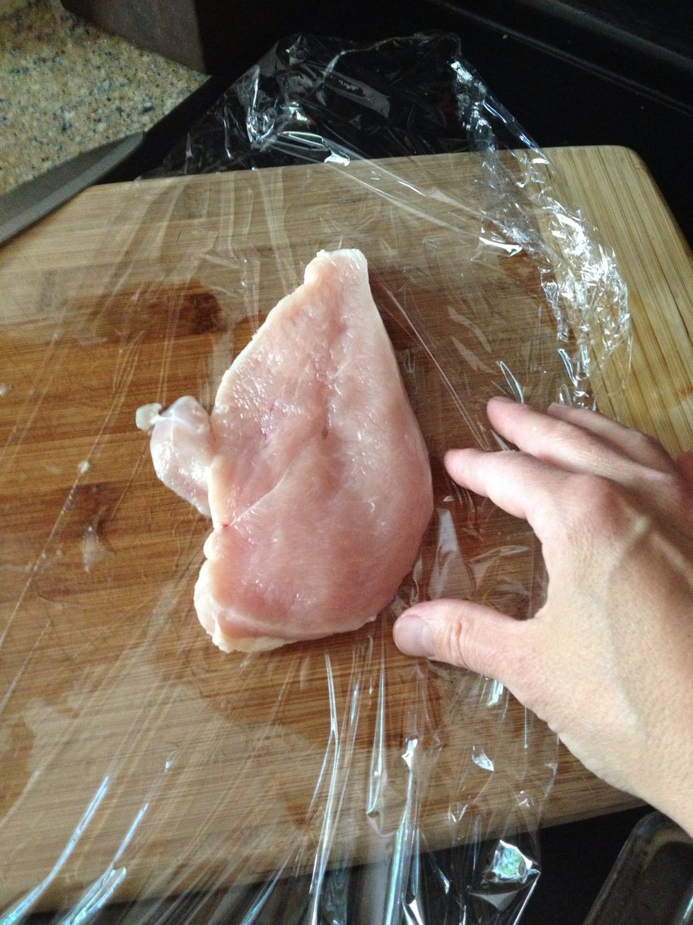 Then take the halved breast piece and lay it between some plastic wrap so you can make the piece thinner.
