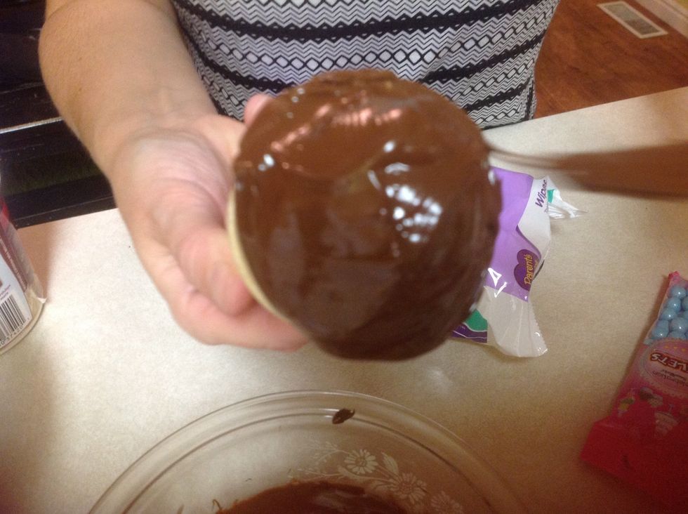 Then take the pops out of the fridge and get the melted chocolate and dump the chocolate on the pops.