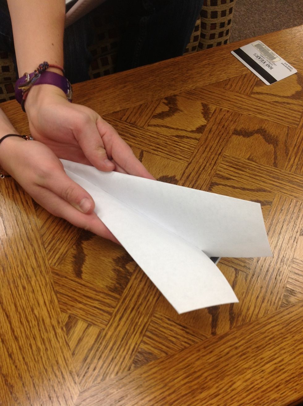 Then, take your paper airplane and fold it like a hot dog bun.