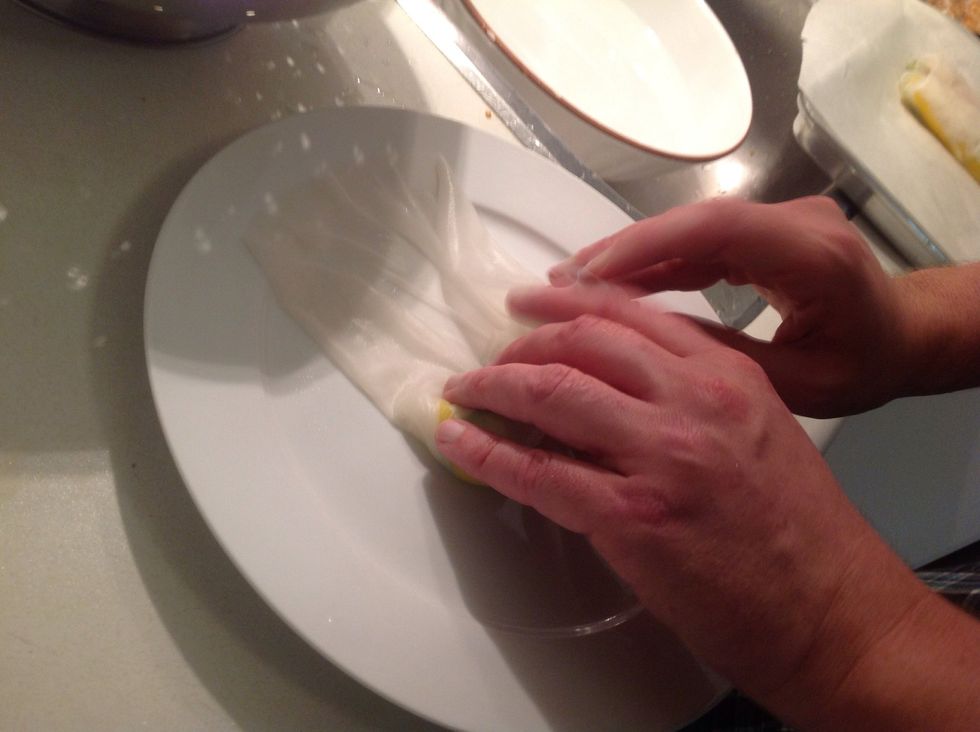 Then the opposite side over toward the middle. Now roll the whole thing forward, pinching the filling to keep it tight. But not so tight that you'll break the wrapper.
