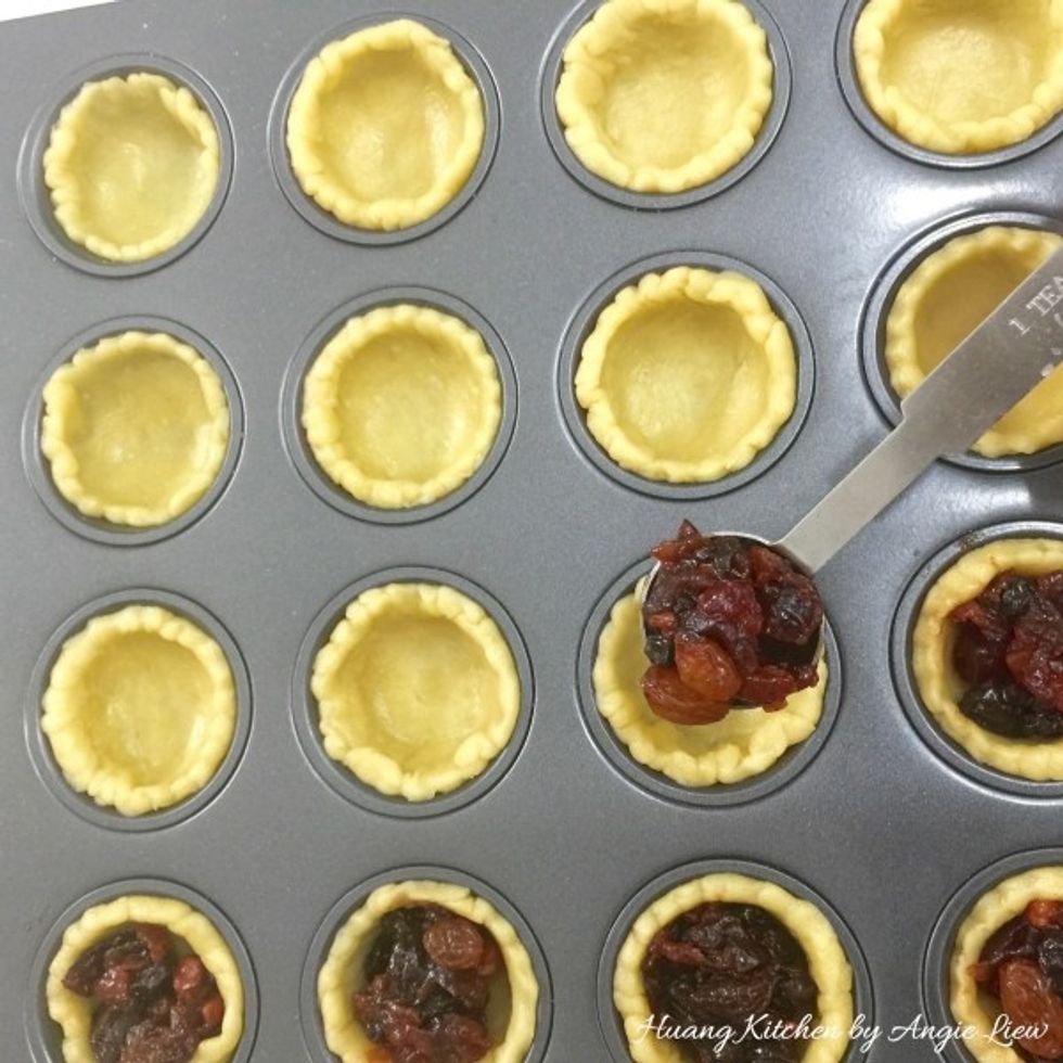 Then top with a heaping teaspoon of mincemeat in each of the cut pastry cup in the muffin pan.