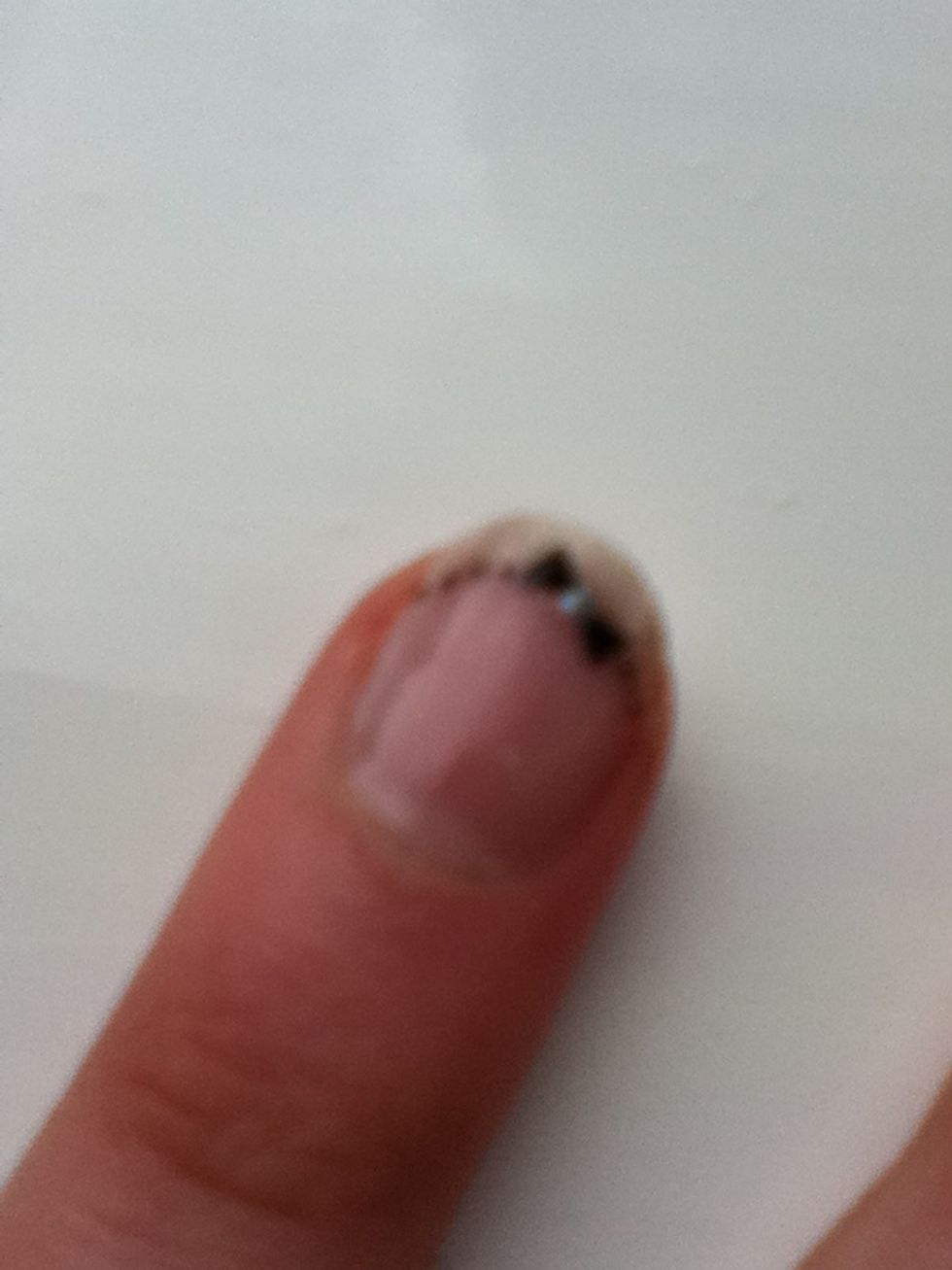 Then using a black nail art pen or a pencil, draw two triangles either side of it to form a bow. Then using the dotting tool, draw small dots wither side of the bow.