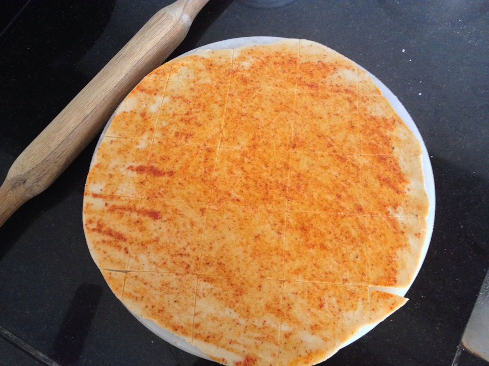 Then using a sharp knife cut the rolled dough in squares as shown. The squares should be like 1.5 inchs in size .