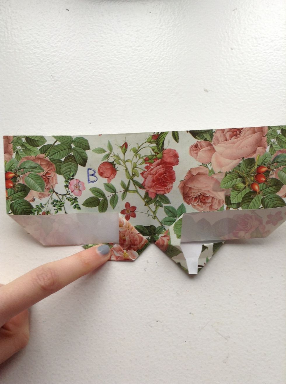 Then you fold the small flaps and fold them in. And they are going to be the the top of the heart. It should look like where my finger is.