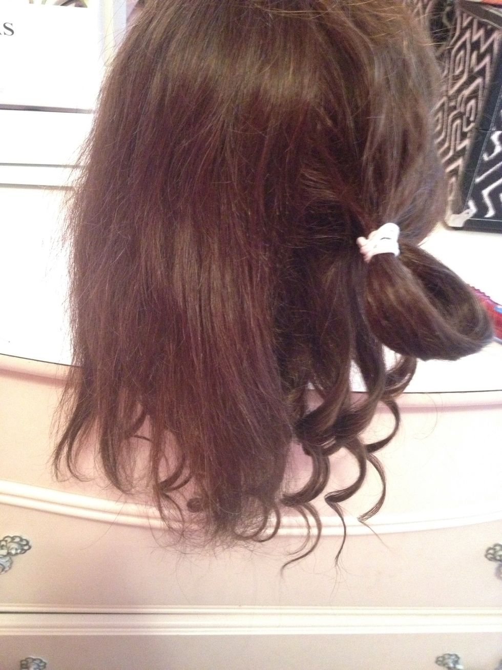 Then you're going to split the top section into half and tie one of the two top sections with a hair tie. Brush the non-tied hair carefully.