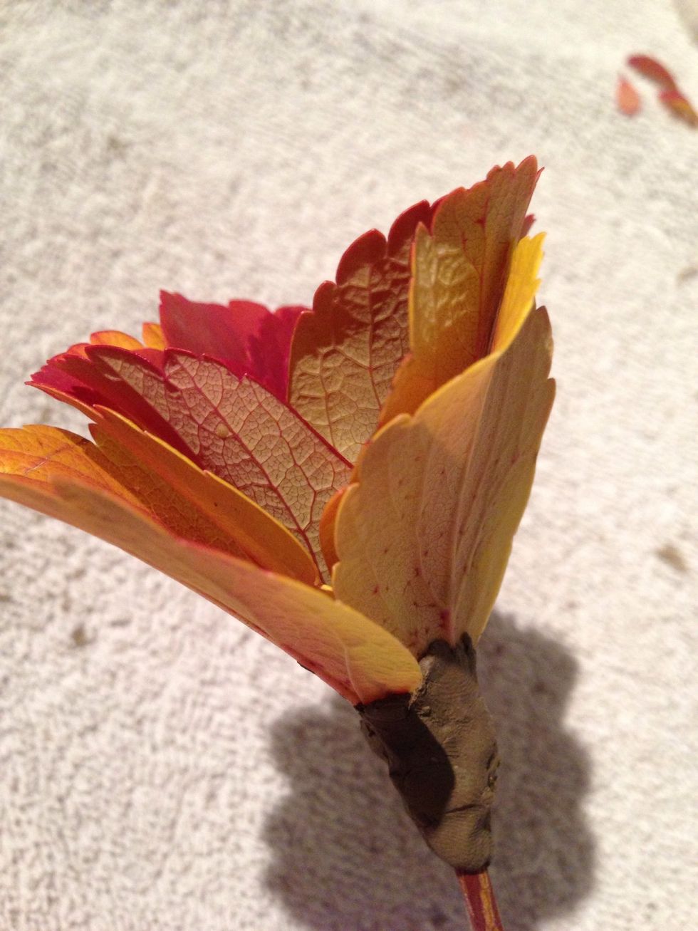 Then you take the stem you picked the leafs from, and fasted the flower you just made with some clay