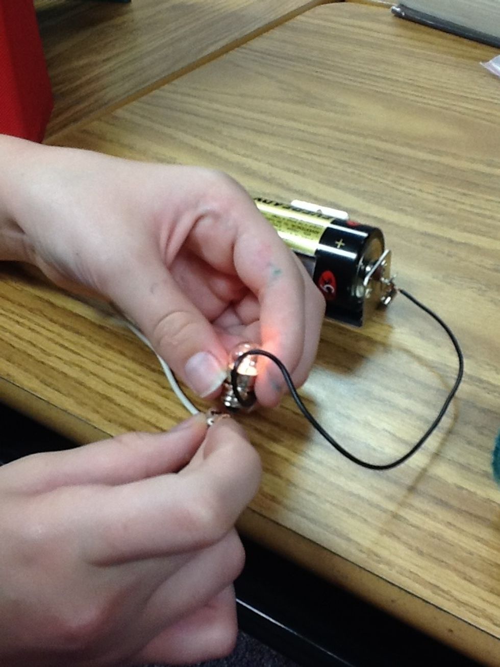 Then you wrap a wire around the top of the lightbulb (as shown in the picture above). And the put the other wire on the bottom of the light bulb to make it light up.