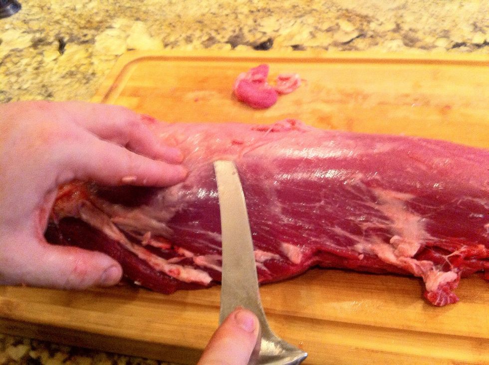 There is still a lot of fat and membrane that needs to be cleaned from the loin. Slide the tip of your knife just under the surface of the membrane, making the cut as shallow as possible.