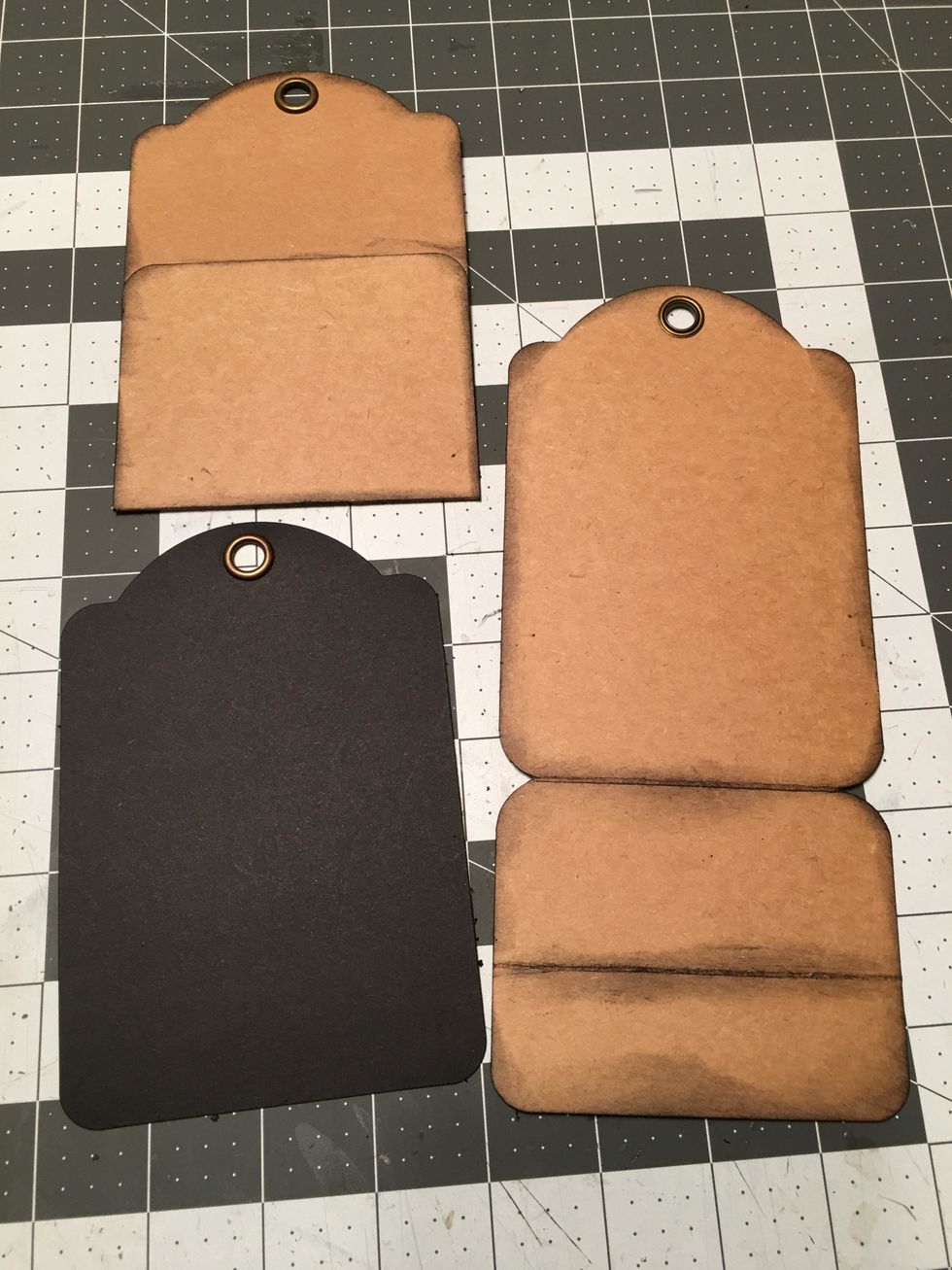 These are the pieces for your tag album: 6 black regular tags with no pockets, 5 large kraft tags with pockets folded and 1 large kraft tag with scored section on the bottom for the wrap around cover