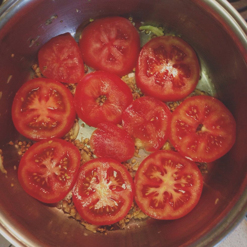 Thickly slice the remaining tomatoes and place over the saut\u00e9ed garlic and coriander.
