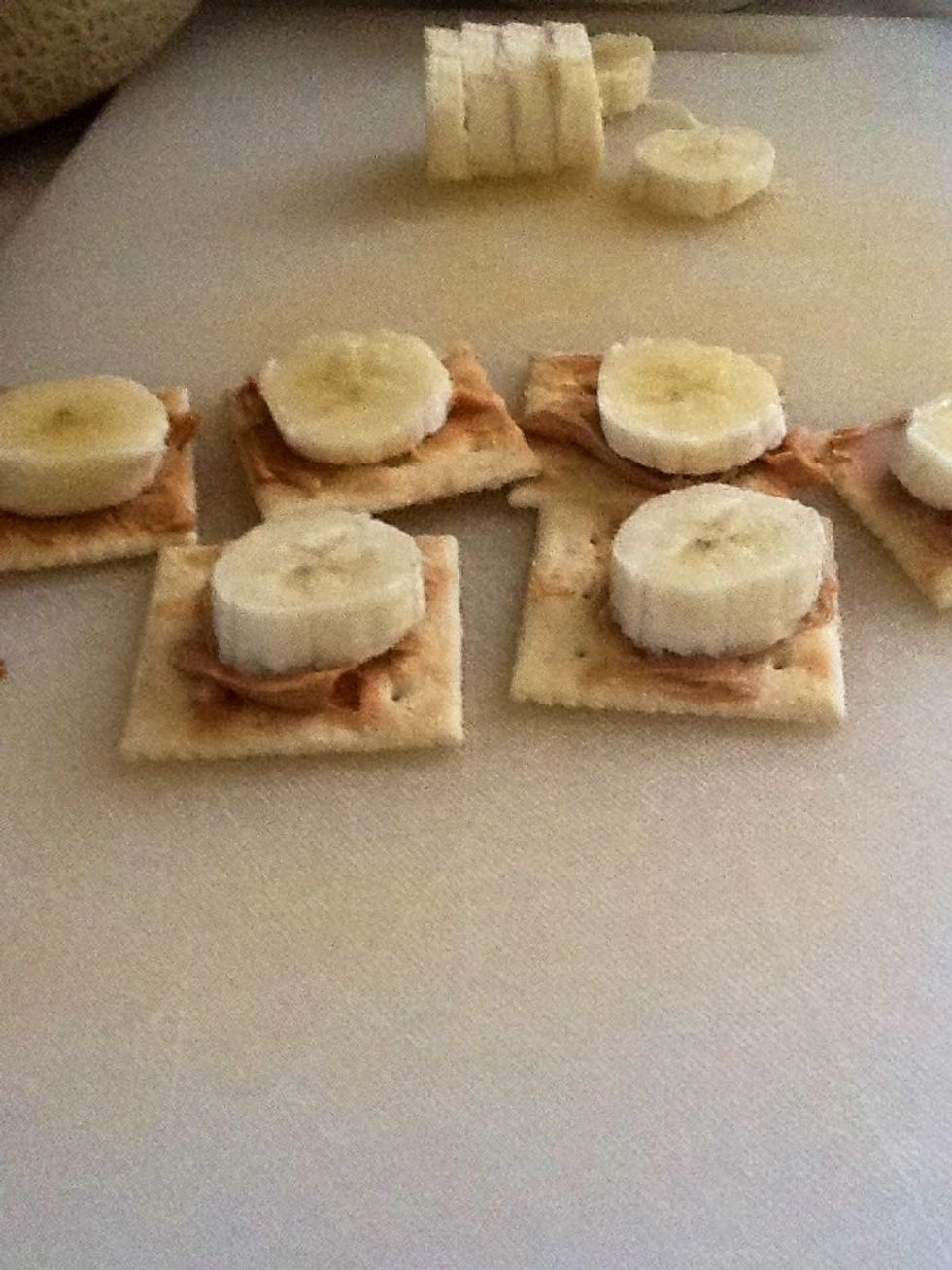 Third add the banana slices on top of the peanut butter and soda crackers.
