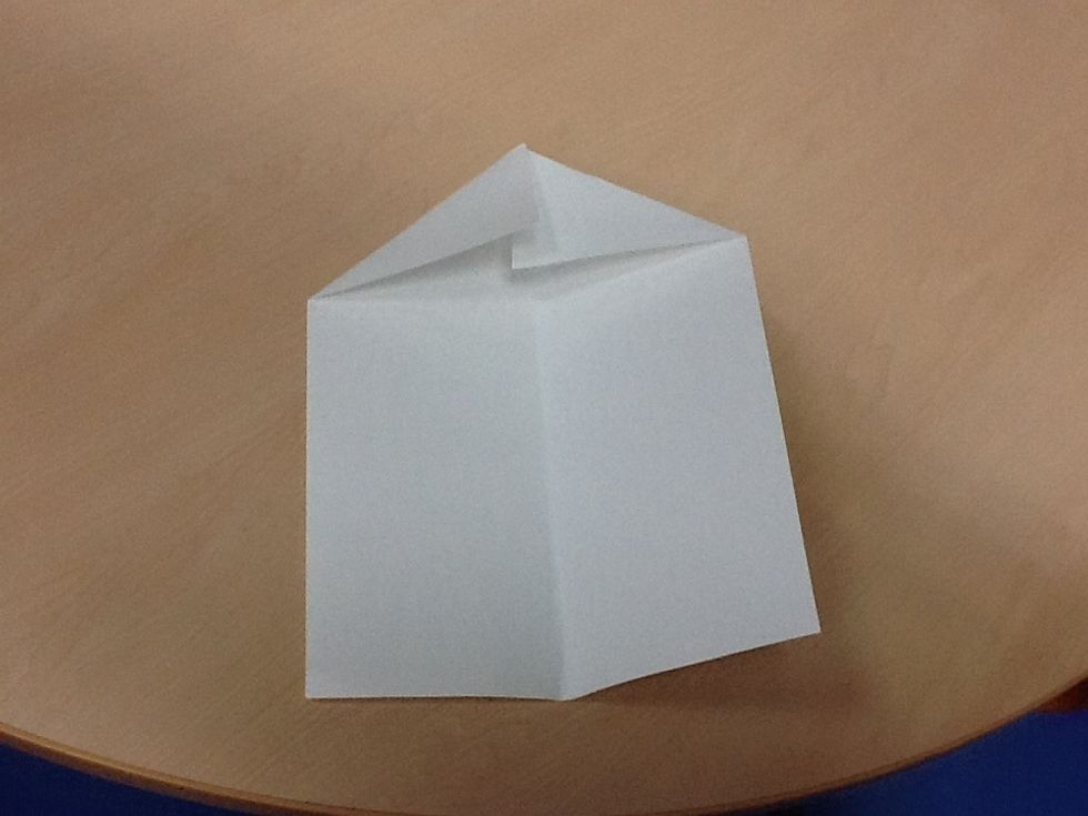 Third, fold the top corners of the paper to where you folded the paper in half.