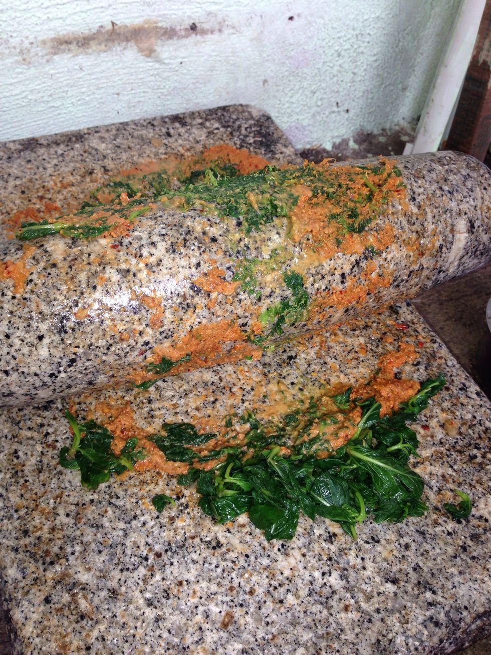 This is a metate (ground stone tool). Grind all the ingredients including tamarind paste and followed by the leaves. U can use mixer grinder instead of metate.