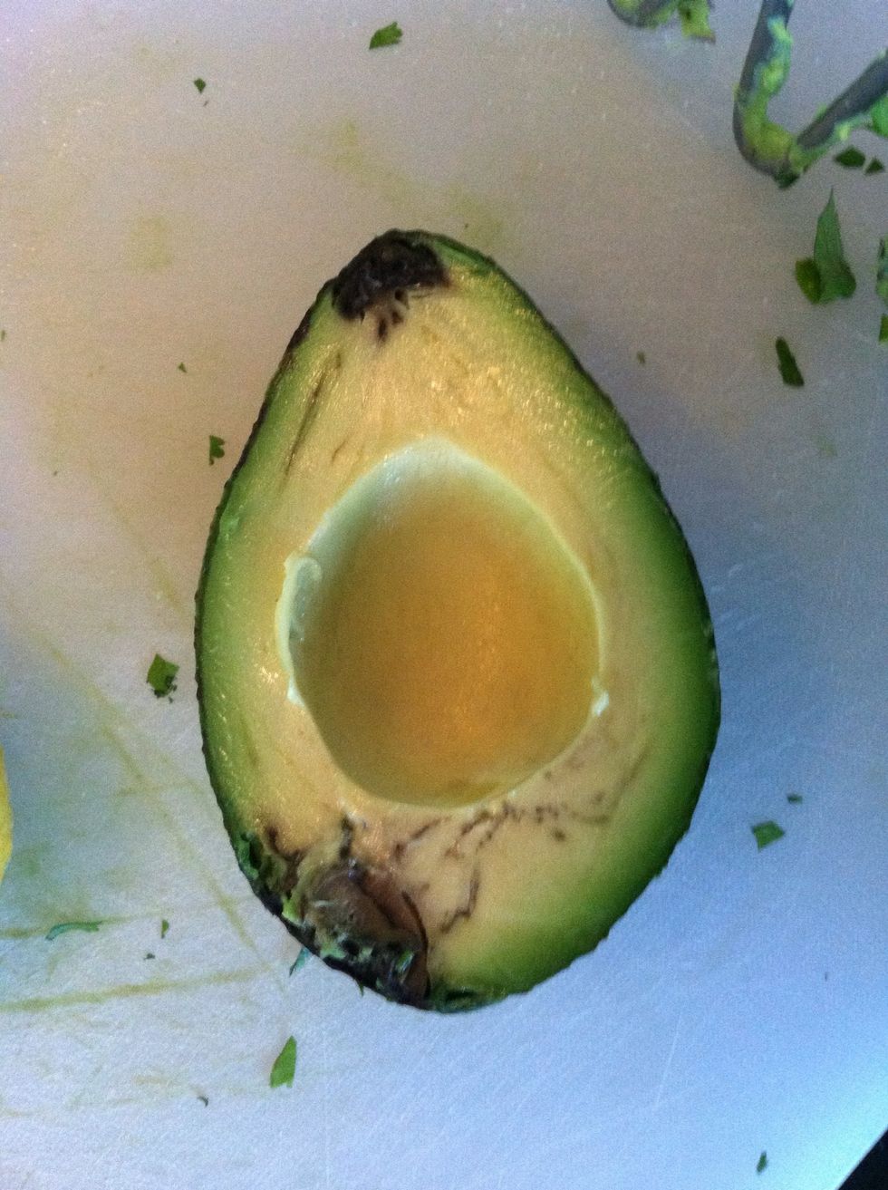 This is an avocado gone bad, as you can tell by the black spots. It's common to find one bad or bruised one in the bunch. You may be able to save some of it by using only the parts that aren't black.