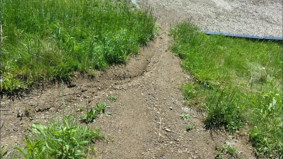 This is an example of Erosion because the wind is moving the weathered ground down the hill.