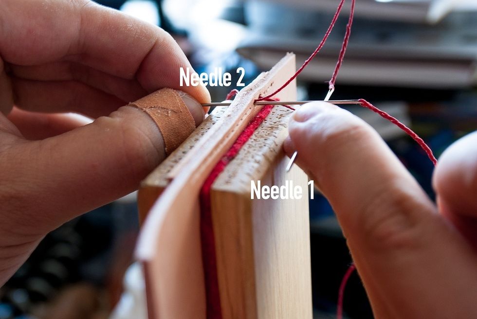 This is another view of needle 2 going through the same hole. Note that the needle is closer to you than the thread. Don't switch that around or your stitches will be uneven.