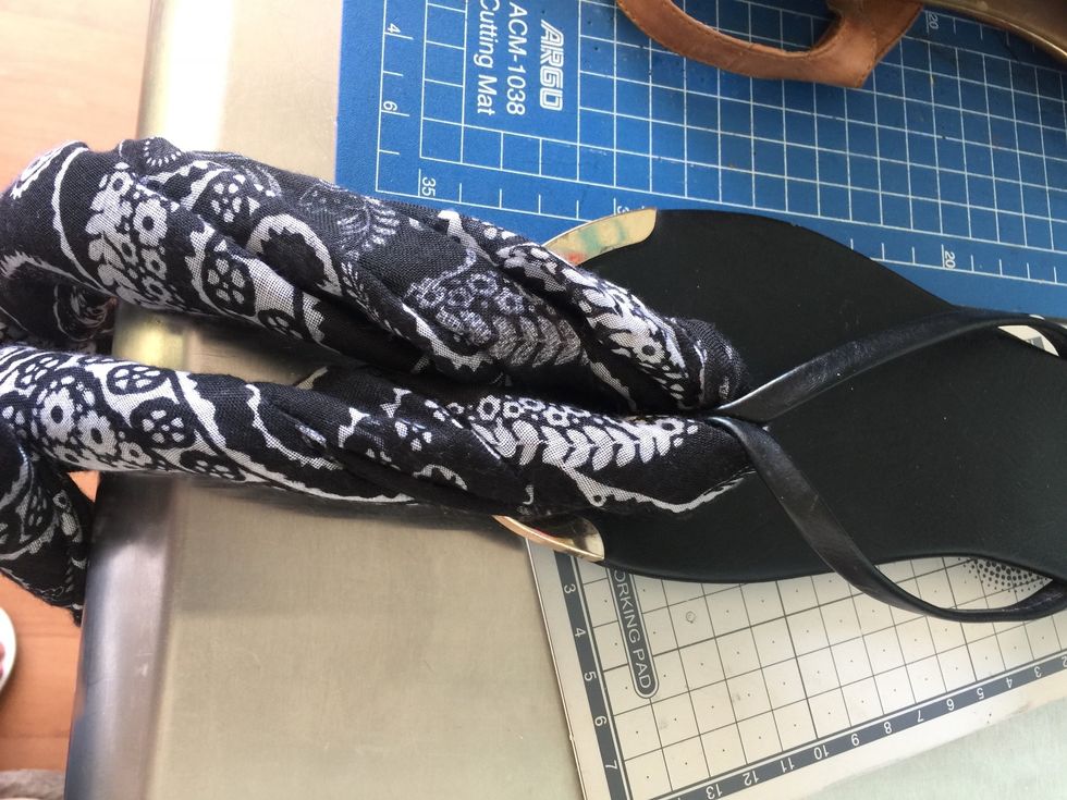 This is more clear, but you have to go through the sandal in half the scarf and then pull the other side inside the knot yo make stay in place