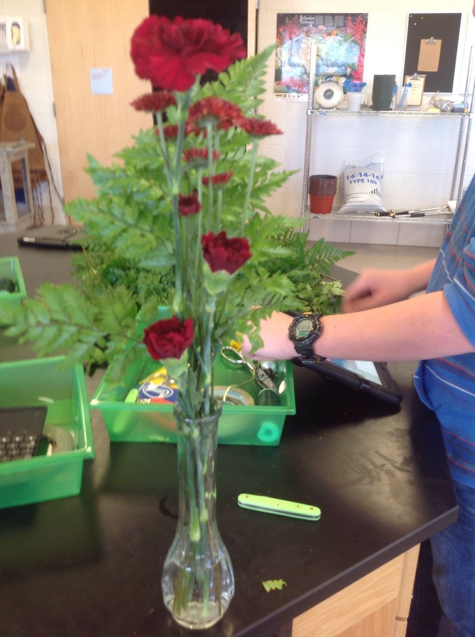 This is the Bud Vase almost finished with three red carnations, Leather Leaf, and now also red mums.