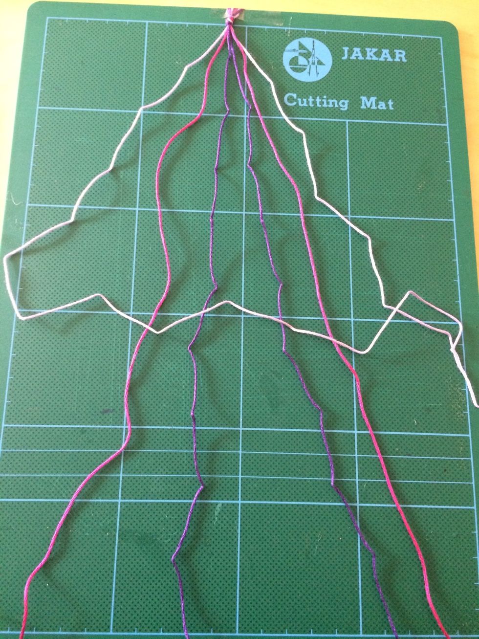 This is to make a chevron style bracelet. Starting with the pale lilac (far left) thread, make an 'L' shape across the other threads.