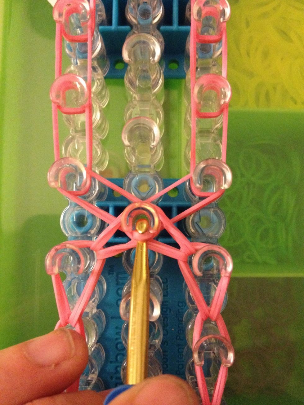 This is where it can get a little hard. Reach in the center peg and grab the first two bands on top. Move them to the left. Go back in the center peg and grab the last two bands and go the right.