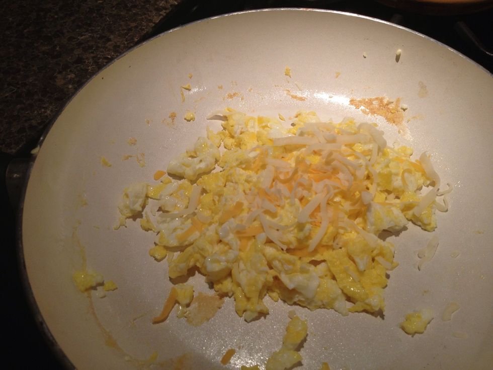 This step is Optional take the shredded cheese and sprinkle some on top of the eggs