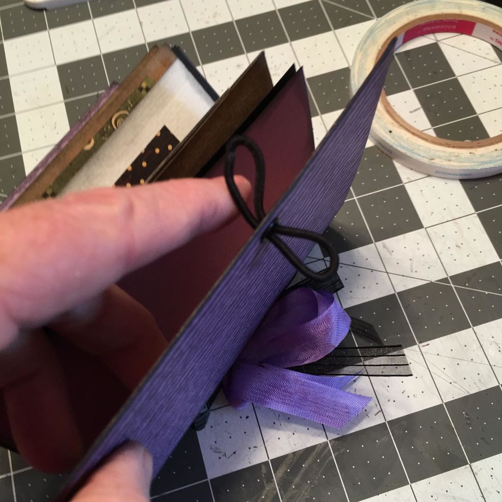 Thread a black ponytail elastic through the eyelet on the cover as shown.