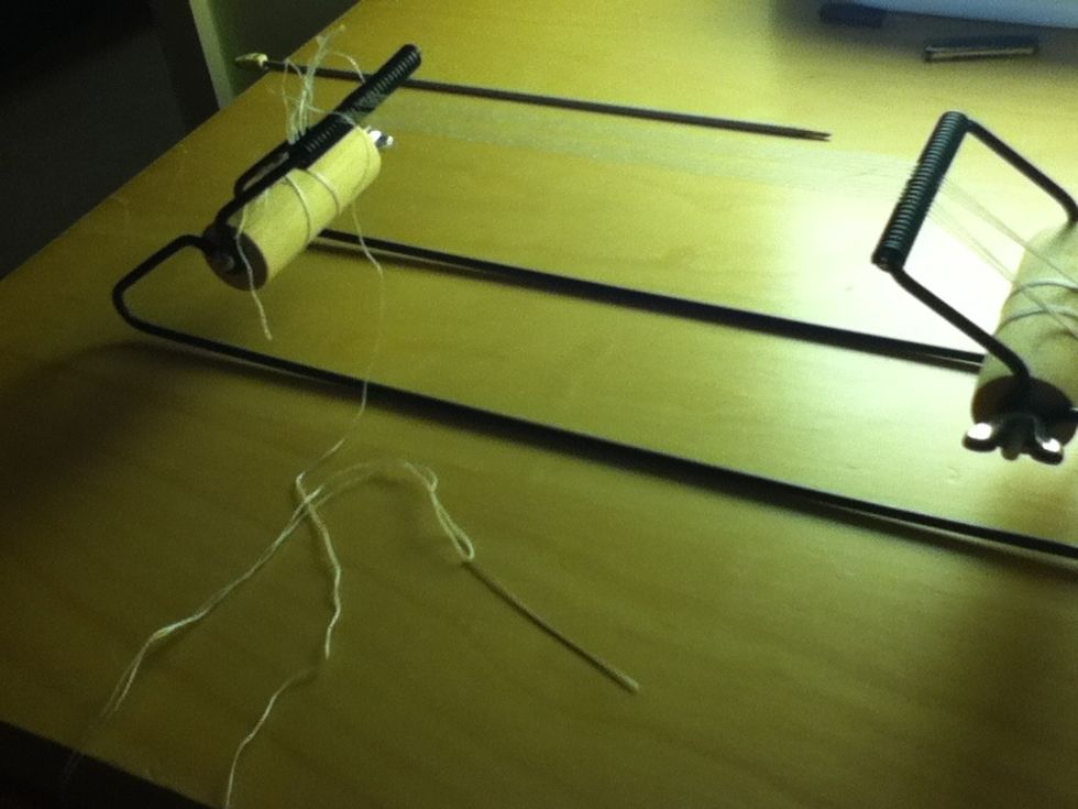 Thread a needle and tie the thread on the last string on the loom