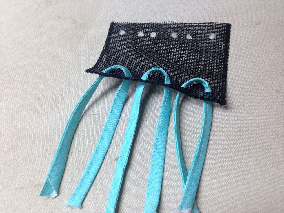 Thread each utensil strip through the bottom holes of the pocket \u2013 back to front as shown.