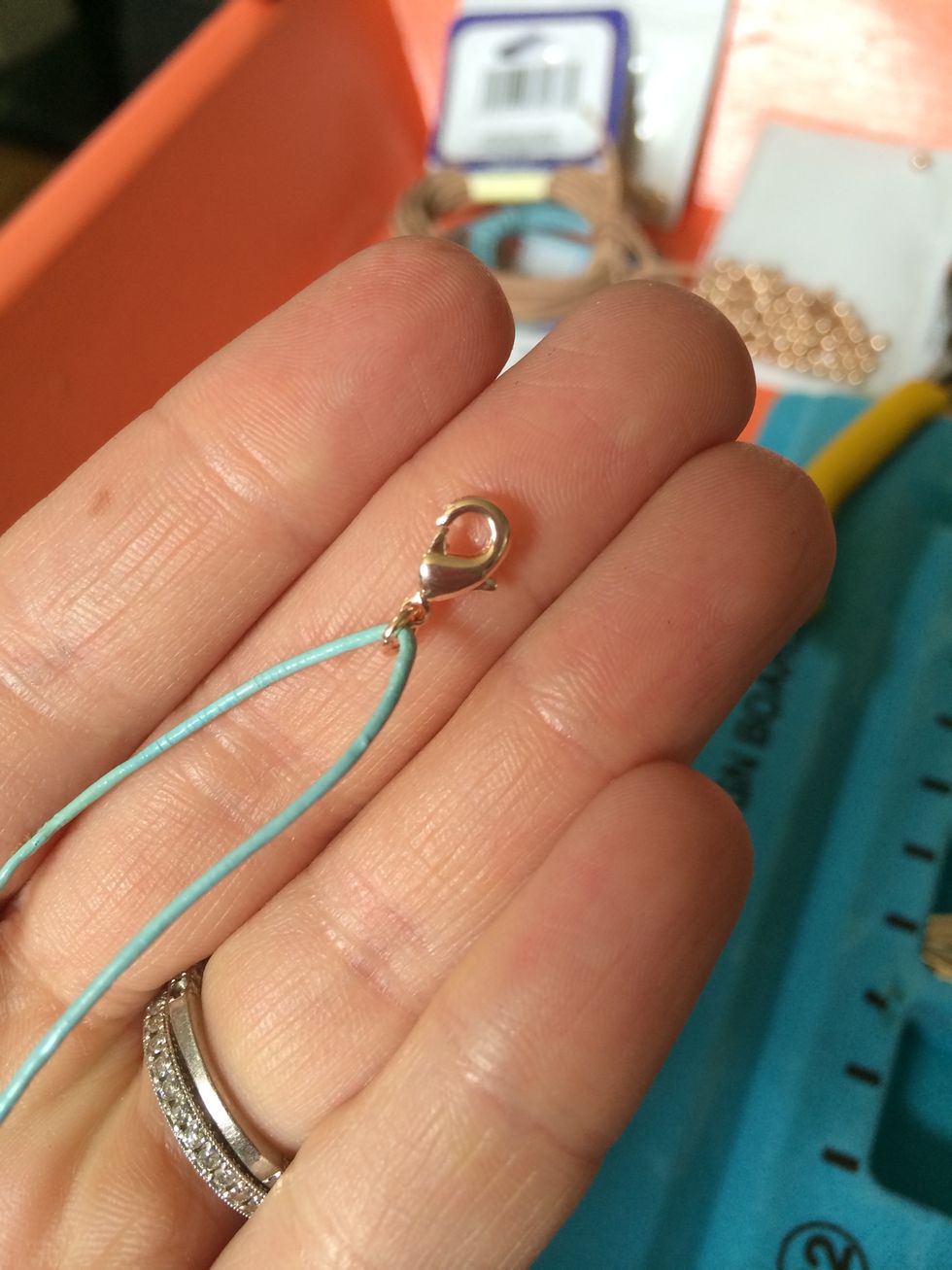 Thread the cord through the jump ring on the clasp.