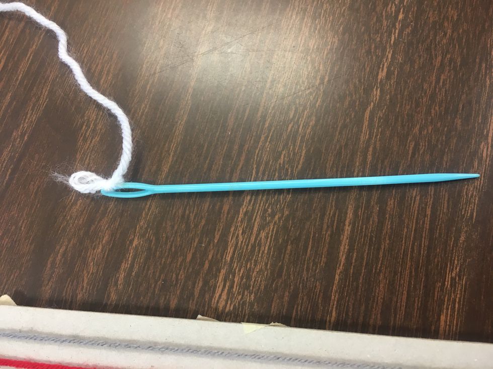 Thread the other piece of yarn through your weaving needle, and secure it with a knot.
