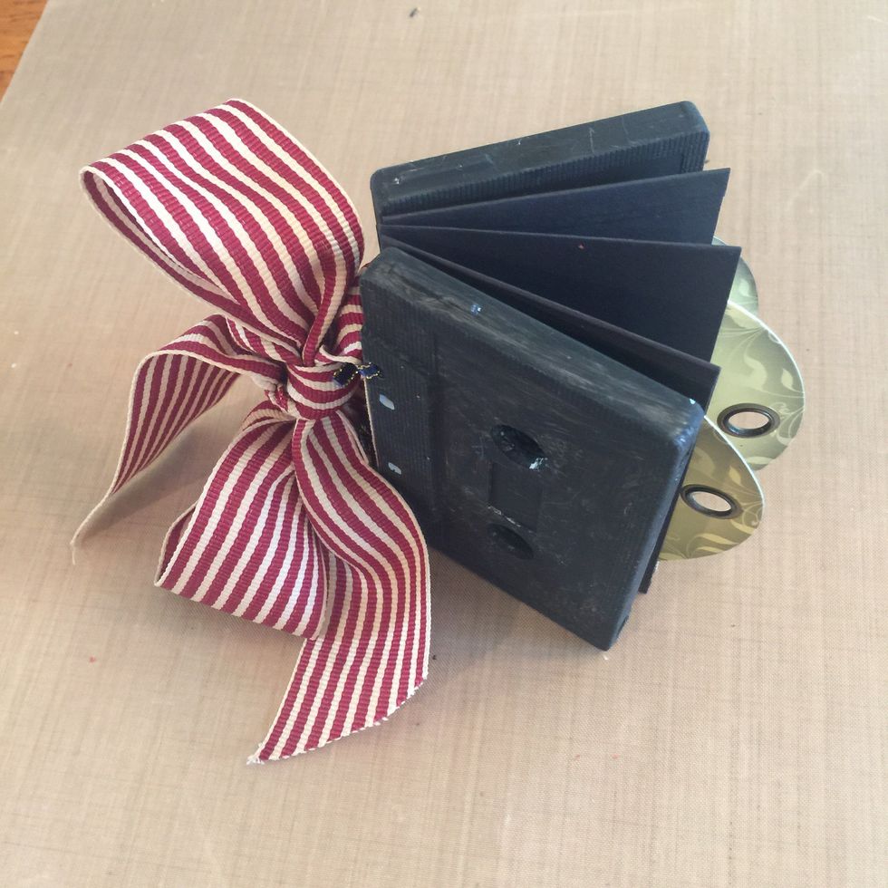 Thread wide ribbon through loops of thin ribbon and make a prett6 bow to decorate the album "spine".